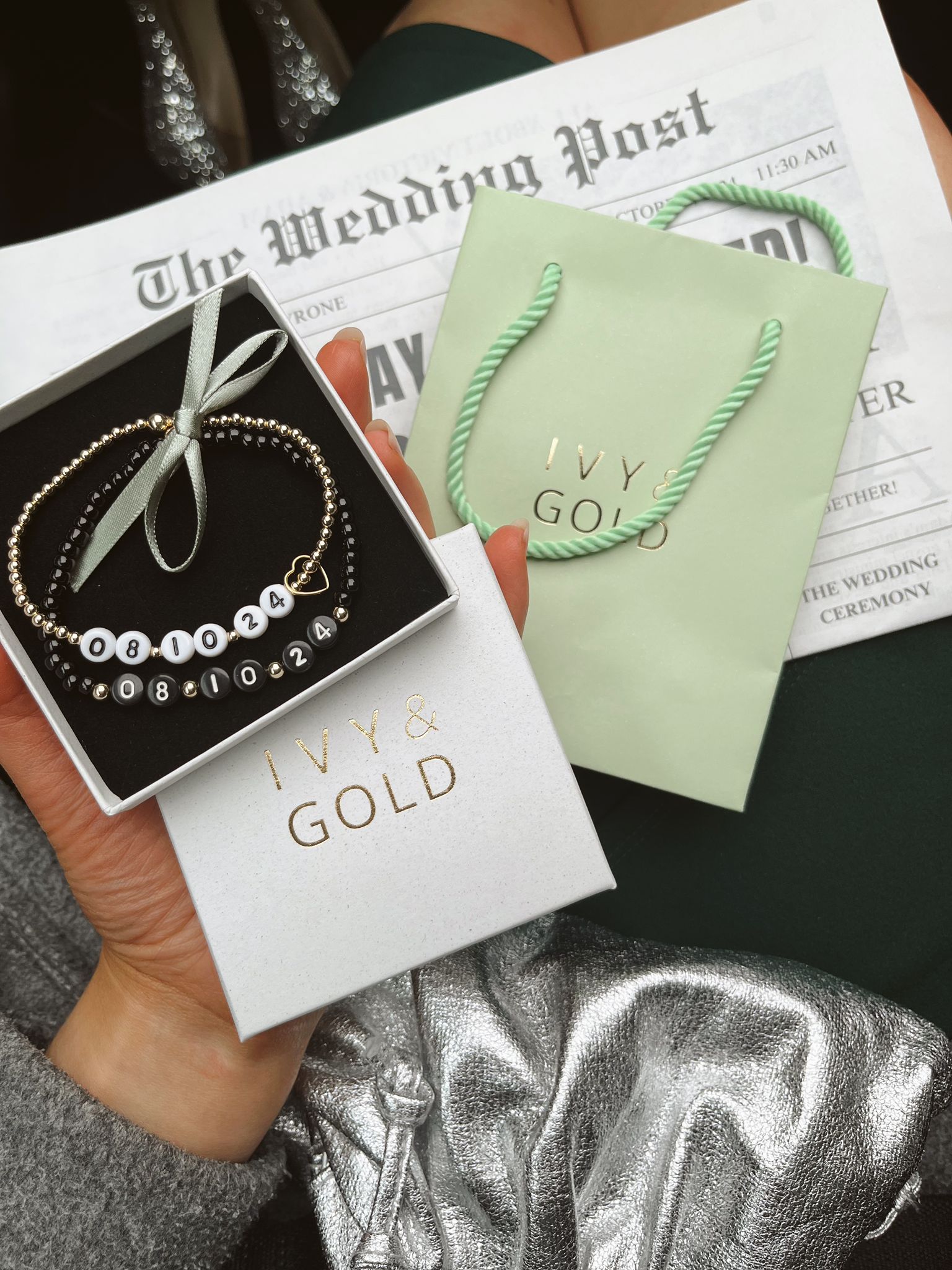 Bracelets in a 'IVY & GOLD' box with a green bracelet on a newspaper background
