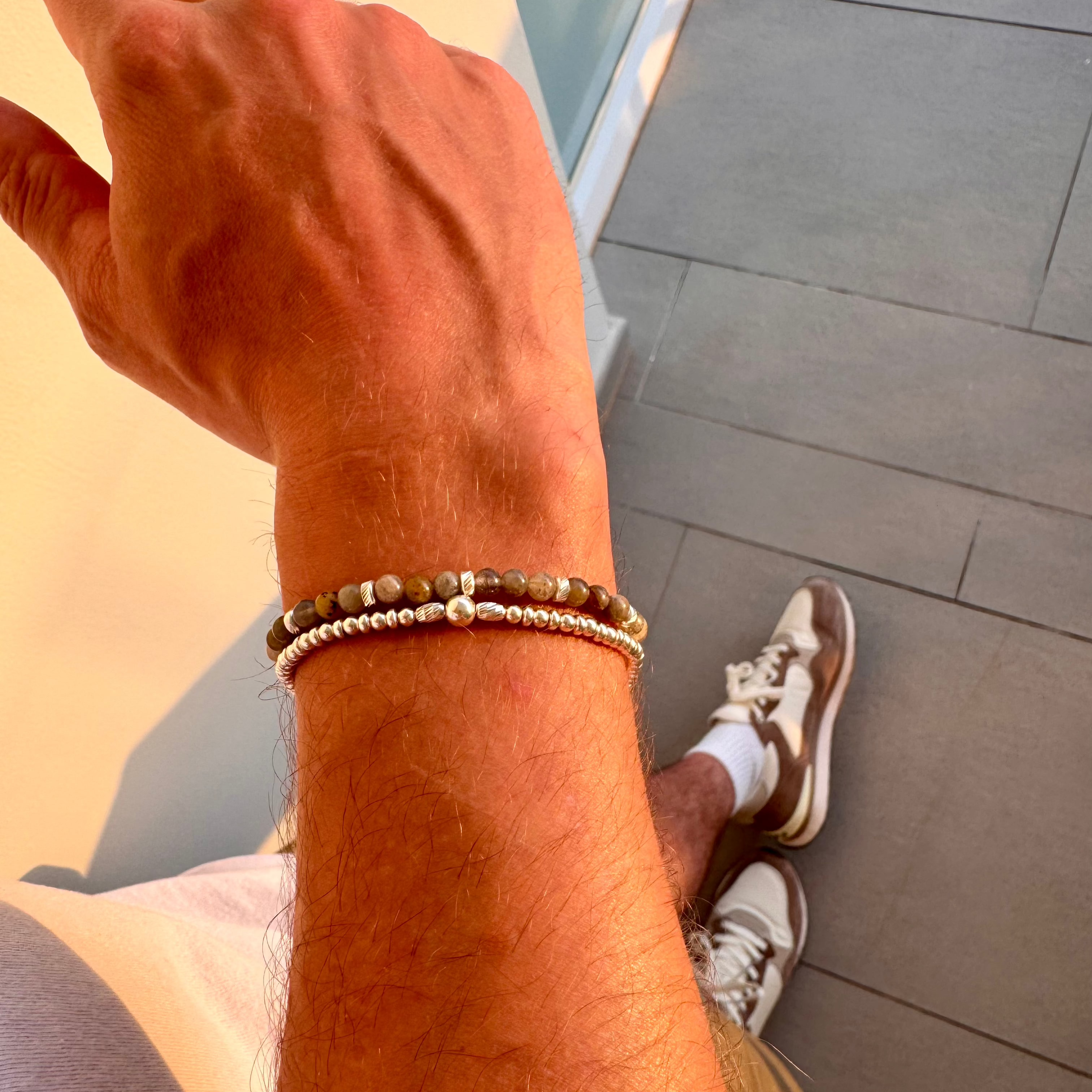man's arm wearing silver and labradorite bracelet stack