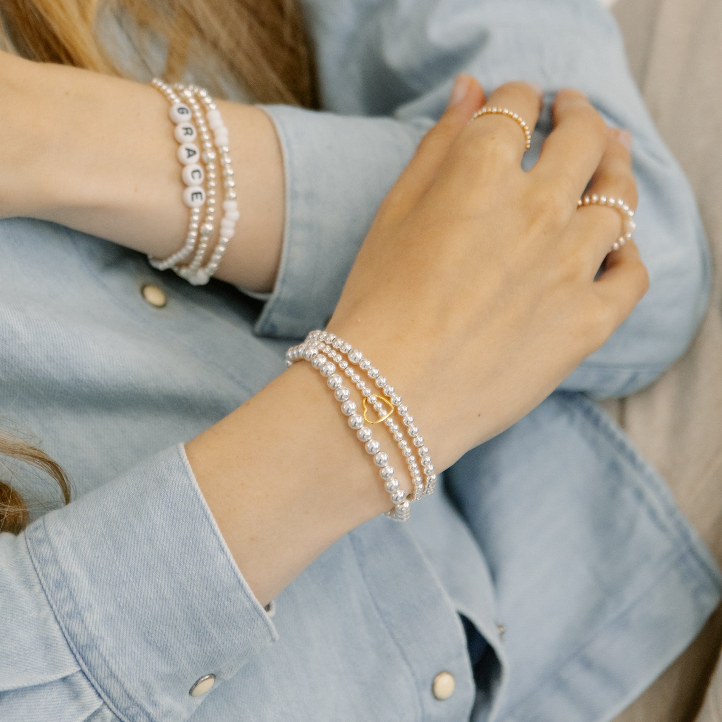 4mm sterling silver bracelet in a stack with a heart charm bracelet and a 5mm sterling silver bracelet 