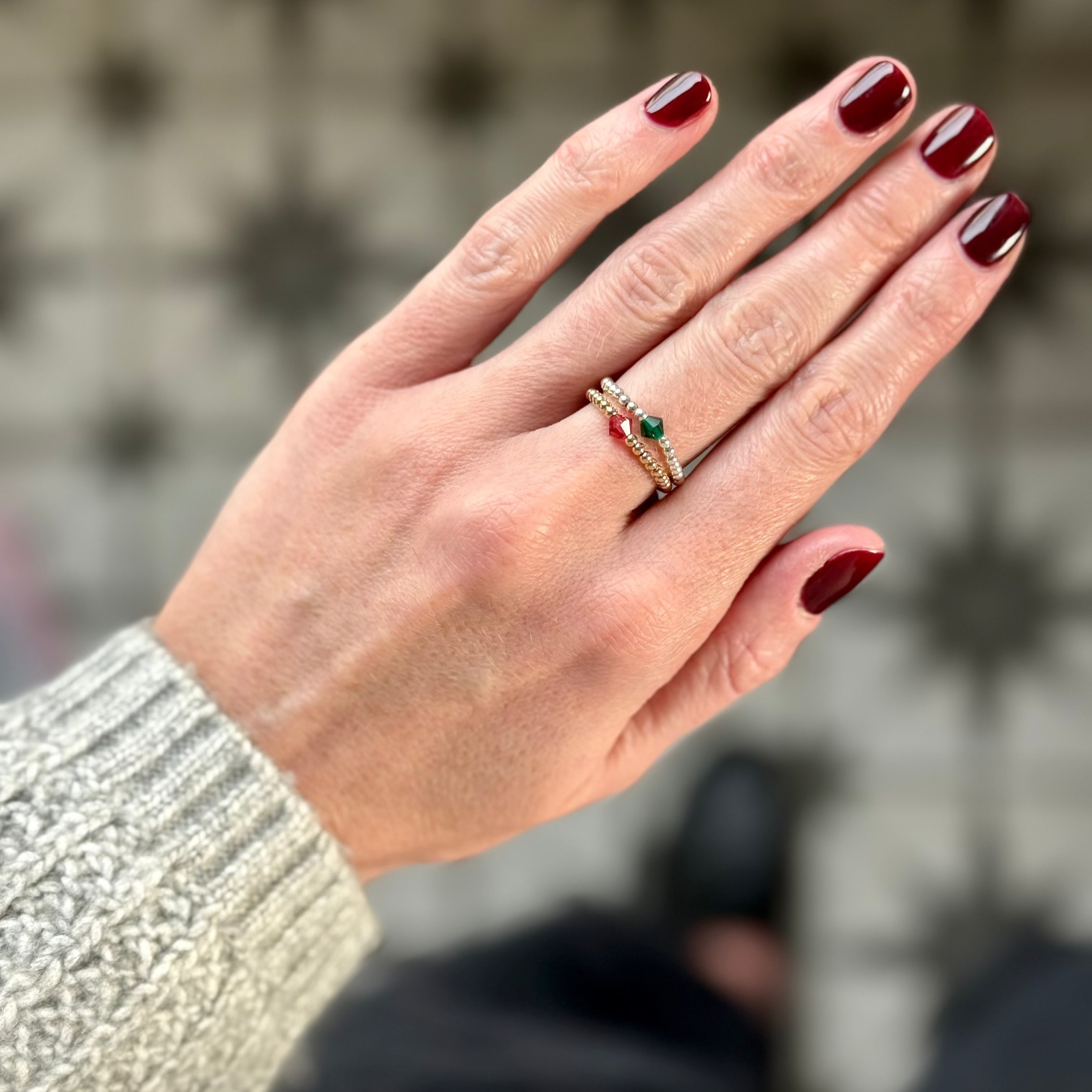 Hand with red nail polish wearing a ring, blurred background