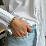 Person wearing a white shirt and light blue jeans with a bracelet on a blurred background