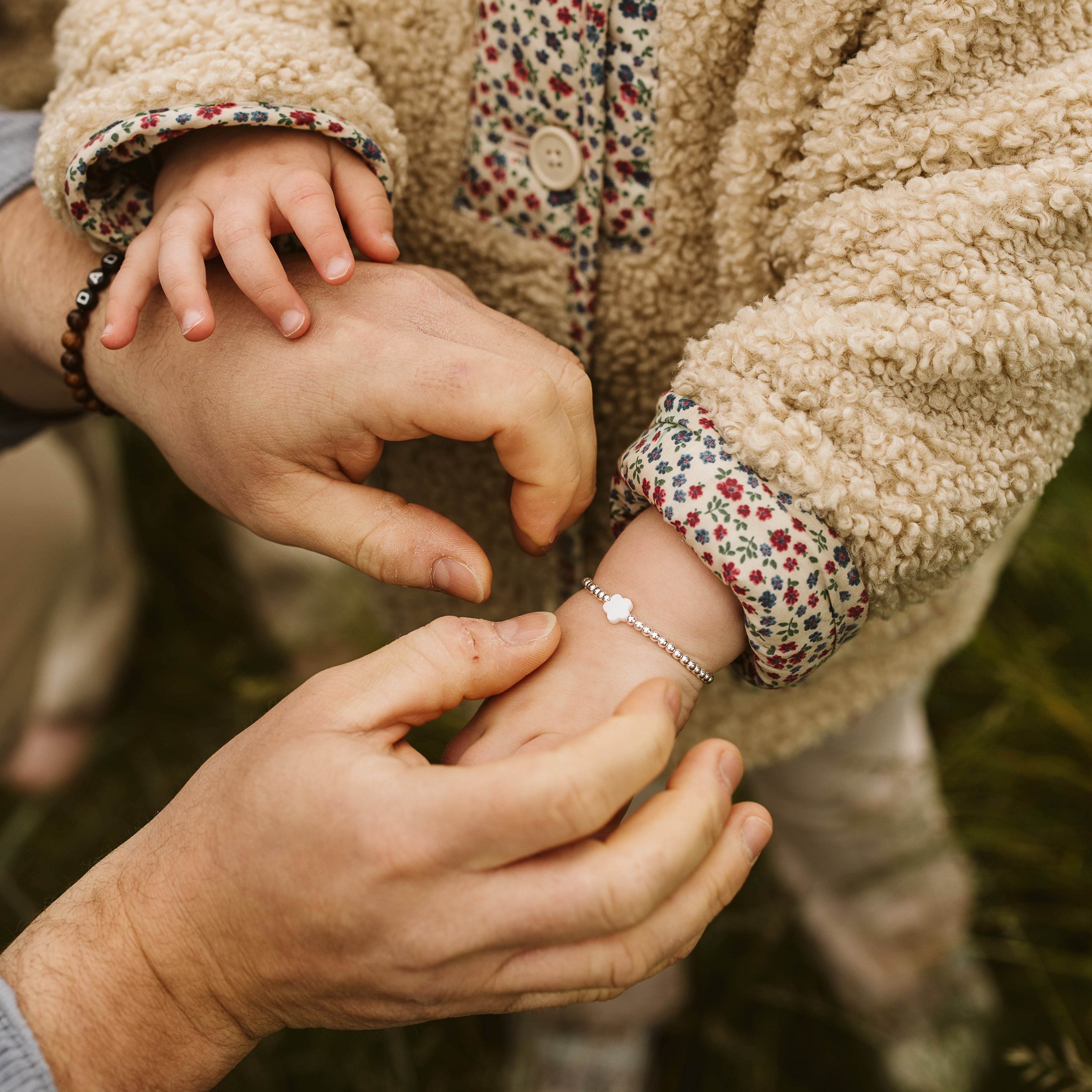 dad putting a pearl flower bracelet on his daughter
