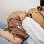 stack of gold filled bracelets on a mum with a baby